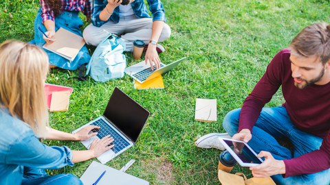 The photo shows several students. They are sitting on a lawn with their laptops and studying. 