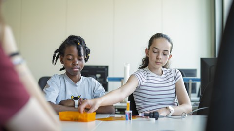 Girls'Day Academy 2025: Mädchen sitzen an einem Tisch und untersuchen Kunststoffe.