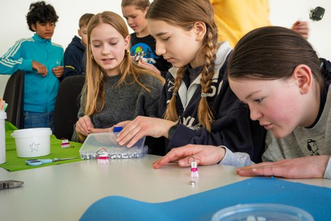 Kinder sitzen an einem Tisch und basteln.