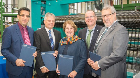 Gruppenbild vor einer Textilmaschine des ITM: Prof. Chokri Cherif (ITM), Prof. Hubert Jäger (ILK), Prof. Brigitte Voit (IPF), Prof. Alexander Michaelis (IKTS), and Prof. Eckhard Beyer (IWS) (v.l.n.r.)