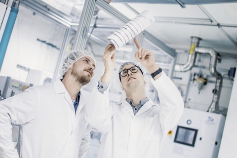 Die RCCF-Wissenschaftler Benjamin Richter und Daniel Wolz begutachten vor der Carbonisierungsanlage die entstandene Carbonfaser.