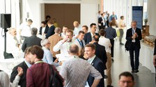 Menschen stehen in einem Foyer, reden, lachen, trinken Kaffee.