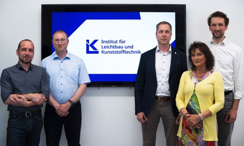Das Institutsboard (v.l.n.r.): PD Dr.-Ing. habil Robert Kupfer, Dr.-Ing. Jörn Jaschinski, Institutsdirektor Prof. Dr.-Ing. habil. Maik Gude, Dipl.-Ing. Barbara Röllig, Dr.-Ing. Sebastian Spitzer. Mittig ist das neue ILK-Logo auf einem Bildschirm zu sehen.