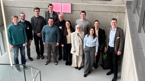 Eine Gruppe von zwölf Personen steht auf einer Plattform und lächelt in die Kamera.
