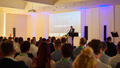 Prof. Gude auf der Bühne vor den Teilnehmern des Leichtbausymposiums.