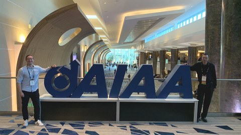 Felix Biertümpfel and Hannes Rienecker on either side of the large AIAA logo