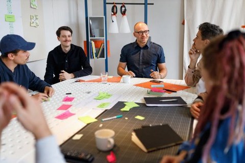 Personen interagieren an einem Tisch in einem kreativen Workshop