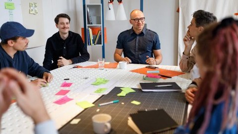 Personen interagieren an einem Tisch in einem kreativen Workshop