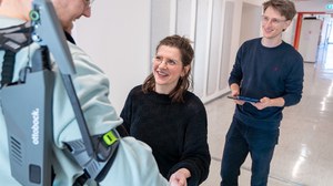 Designforschende begutachten ein Exoskelett.