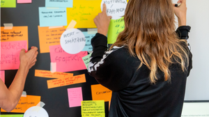 Personen bringen Post-Its an einer Wand an.