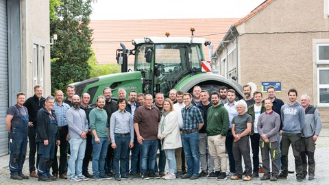 Gruppenfoto der Mitarbeiter des AST mit Traktor im Hintergrund