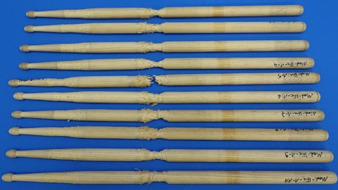 Im Bild sind verschiedene Drumsticks aus der Holzart Hickory nach einem Belastungstest zur Abnutzung dargestellt.