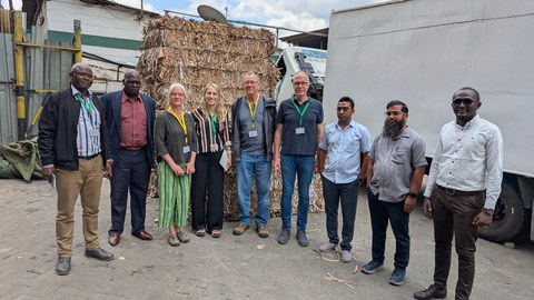 Das Bild zeigt eine Gruppe von Personen aus Kenia und Deutschland vor einem Papierstapel
