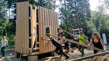 Aufbau einer Biwackhütte, Mehrere Studenten stellen gerade eine Holzwand auf