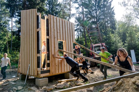 Aufbau einer Biwackhütte, Mehrere Studenten stellen gerade eine Holzwand auf
