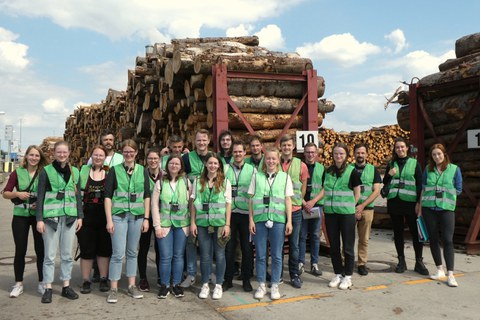 Gruppenfoto bei Kronospan vor Holzstapel
