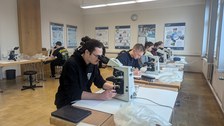 Das Bild zeigt eine Gruppe von Studenten beim Mikroskopieren