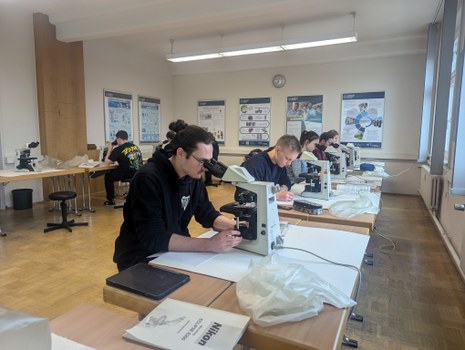 Das Bild zeigt eine Gruppe von Studenten beim Mikroskopieren