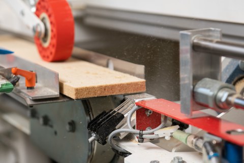 Die Abbildung zeigt den Auschnitt aus der FALSA-Anlage, in der eine Drehvorichtung den abgetrennten Streifen aus Holzfaserwerkstoff neu ausrichtet.