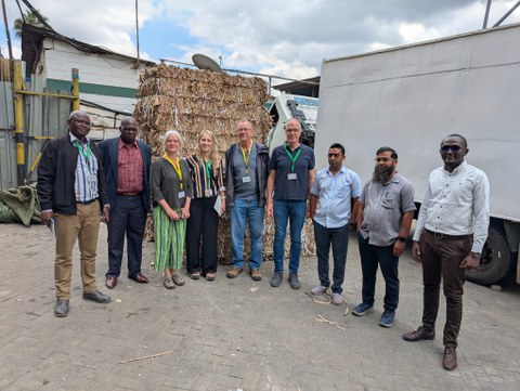 Das Bild zeigt eine Gruppe von Personen aus Kenia und Deutschland vor einem Papierstapel