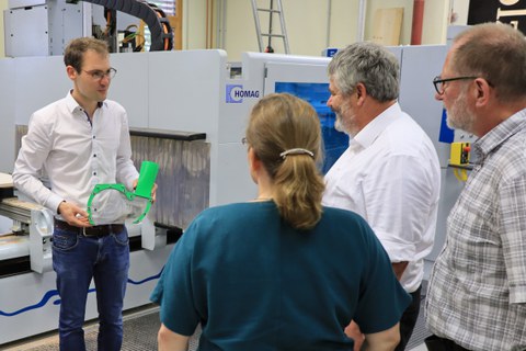 Das bild zeigt einen Wissenschaftler, wie er eine 3D-gedruckte Absaughaube für Holzbearbeitungsmaschinen präsentiert