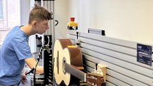Ein Schüler steht vor einer Gitarre