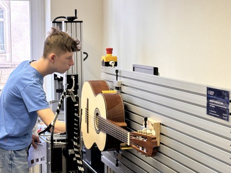 Ein Schüler steht vor einer Gitarre