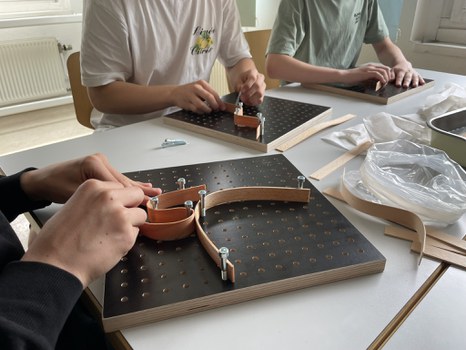Man sieht Hände, die Furnierstreifen in einer Schablone formen