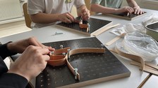 Man sieht Hände, die Furnierstreifen in einer Schablone formen