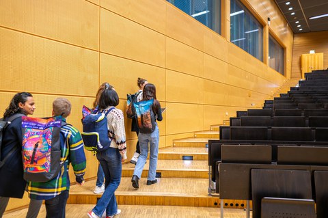 Fotos zeigt sechs Studierende, wie sie in einem Hörsaal auf dem TUD-Campus eine Treppe hochlaufen.