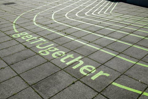 grüner Schriftzug get TUgehter auf Boden aus Betonplatten