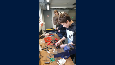 2 Jungen bauen in einer Werkstatt ein Getriebemodell zusammen.