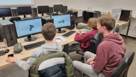 Ein Wissenschtler erklärt zwei Jungen ein Computerprogramm.