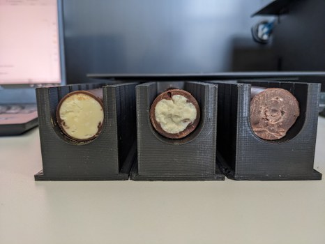 Foto von drei Plastikteilen mit u-förmigen Querschnitten. Darin liegen Stangen aus brauner und weißer Schokolade.