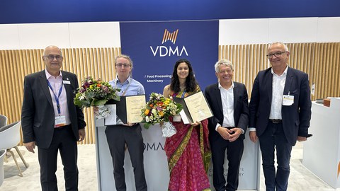 Foto von 5 Personen. Zwei Personen halten einen Blumenstrauß und eine Urkunde. Alle Lächeln in die Kamera.