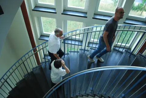 Drei Personen gehen eine Treppe hinauf.