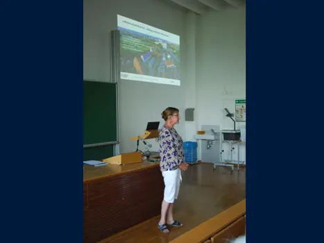 Foto einer Frau, die vor einem Publikum spricht. Im Hintergrund ist eine Präsentation "Wissen schafft Brücken" zu sehen.
