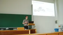 Vortragender Paul Weber mit Präsentation im Hintergrund.