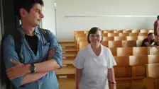 Eine Frau und ein Mann gehen durch den Hörsaal.