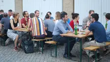 Foto von Menschen auf Bierbänken.
