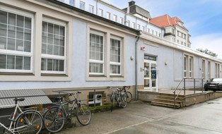Das Foto zeigt den Eingang von Haus D in Dobritz, man sieht davor Fahrräder.