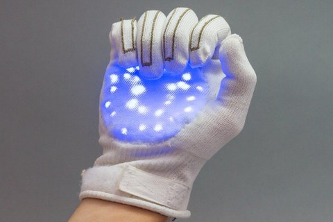 Das Foto zeigt eine rechte Hand, die einen weißen Handschuh trägt. Auf der Innenfläche des Handschuhs sieht man eine blaue Fläche mit weißen Punkten, die so wirkt als sei sie auf den Handschuh projiziert.