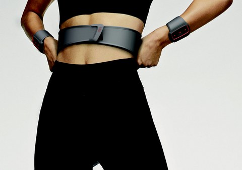 Foto einer sportlichen Frau, die einen Gürtel um die Taille und zwei Armbänder trägt, welche Vibrationssignale aussenden.
