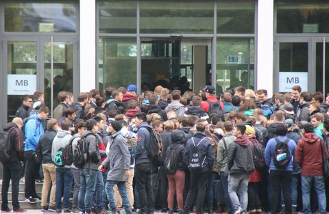 Das Foto zeigt viele Studierende von hinten. Eine große Traube steht vor einer Tür. Auf der Tür steht in Großbuchstaben MB für Maschinenbau. Das Foto zeigt die neuen Studierenden am Tag ihrer Einschreibung an der Fakultät Maschinenwesen der TU Dresden.