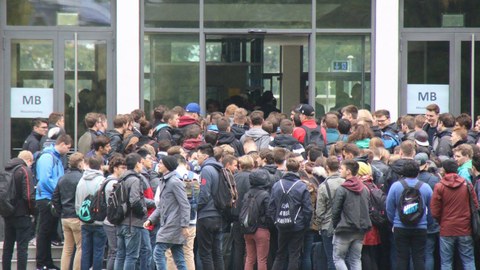 Das Foto zeigt viele Studierende von hinten. Eine große Traube steht vor einer Tür. Auf der Tür steht in Großbuchstaben MB für Maschinenbau. Das Foto zeigt die neuen Studierenden am Tag ihrer Einschreibung an der Fakultät Maschinenwesen der TU Dresden.