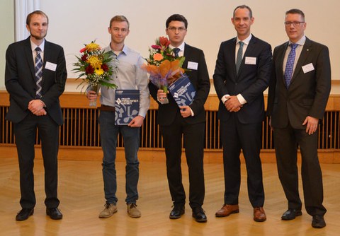 Das Foto der feierlichen Preisverleihung zeigt fünf Personen nebeneinander. Der zweite und dritte Mann von links halten Blumen und Urkunden in der Hand.