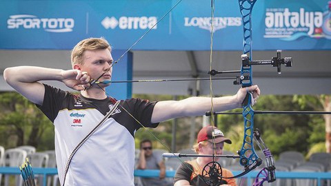 Das Portraitfoto zeigt Leon Hollas, wie er gerade einen Sportbogen spannt und anlegt.