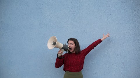 Auf dem Bild ist eine Frau mit einem Megaphon zu sehen