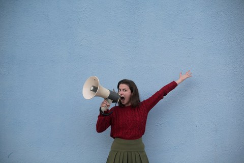 Auf dem Bild ist eine Frau mit einem Megaphon zu sehen