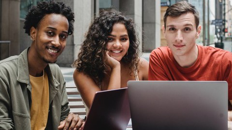 auf dem Bild sind 3 Studierende vor 2 Laptops zu sehen